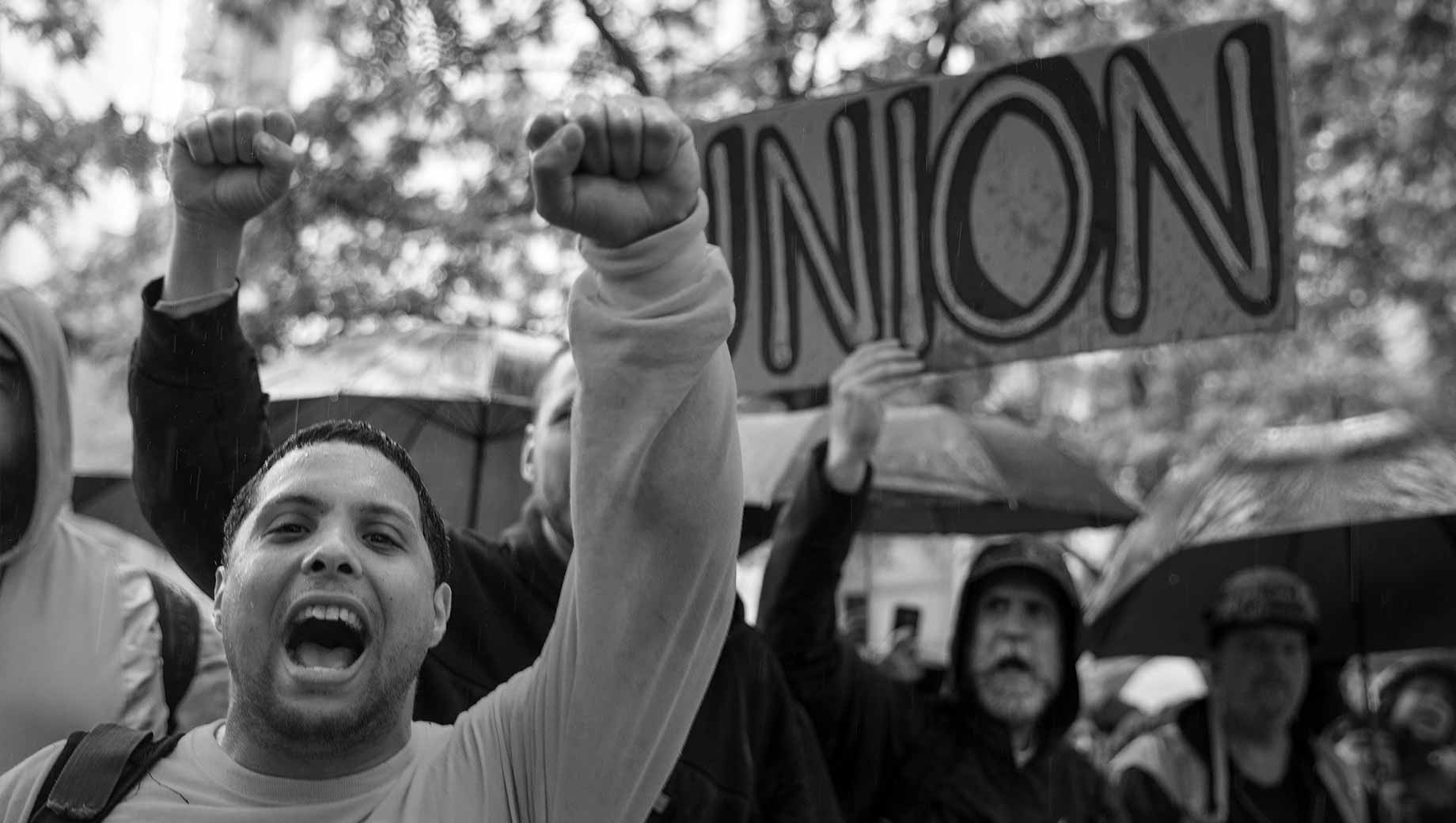Two raised fists in front of a sign that reads "UNION"